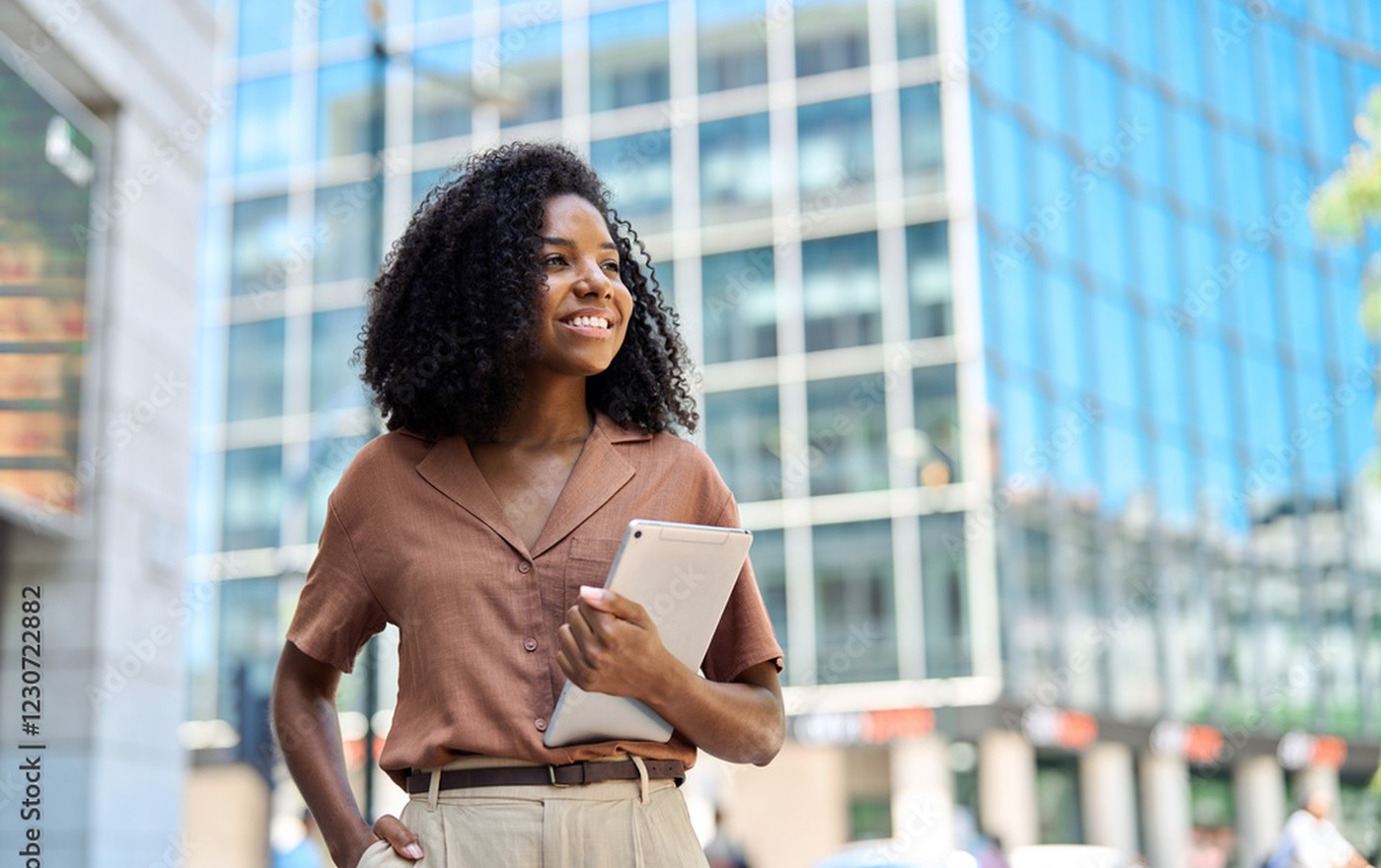 African professional woman with tablet outside modern city office building